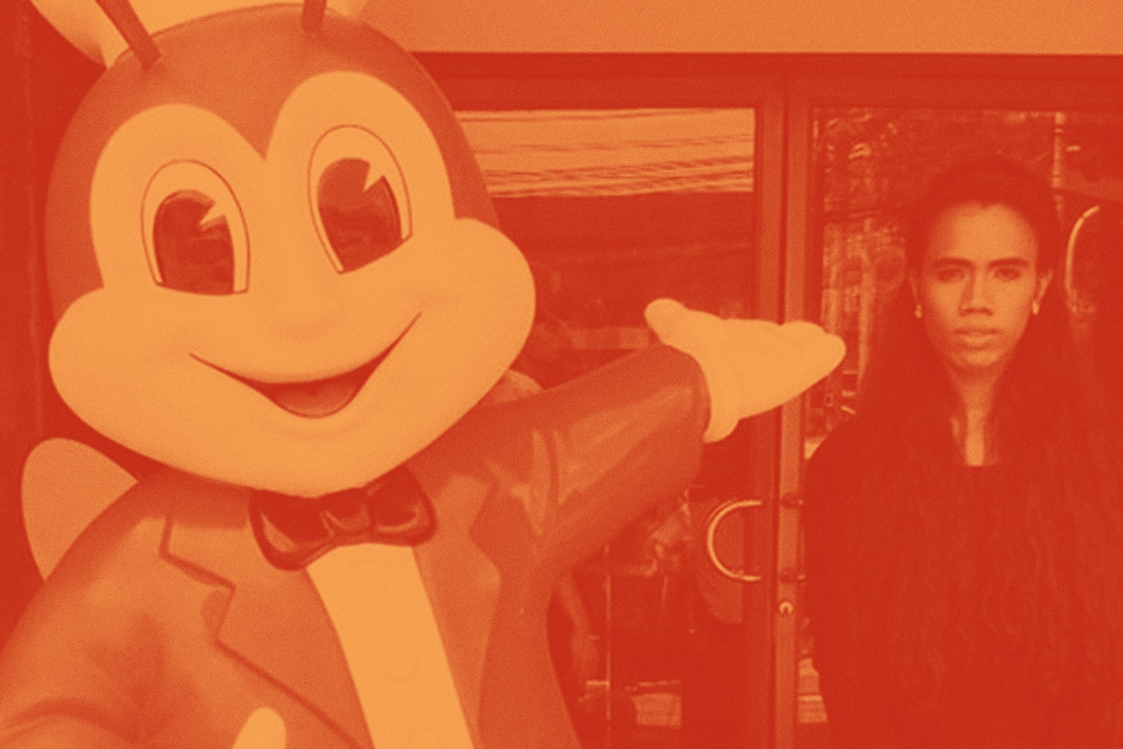 An image of a Jollibee statue pointing at Bunny Carandag, awash in orange.